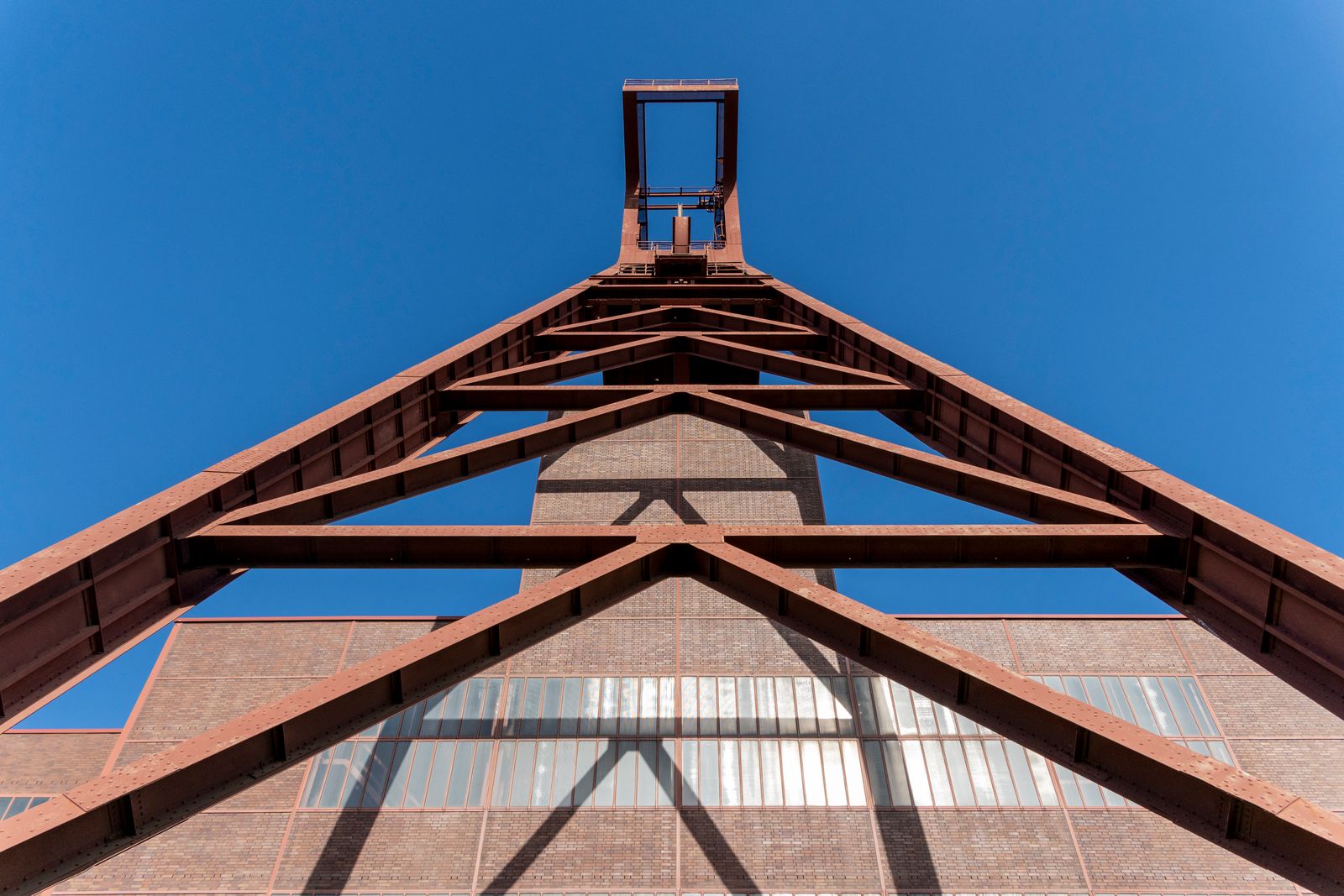 Heavy structural steel framework rising against a clear blue sky